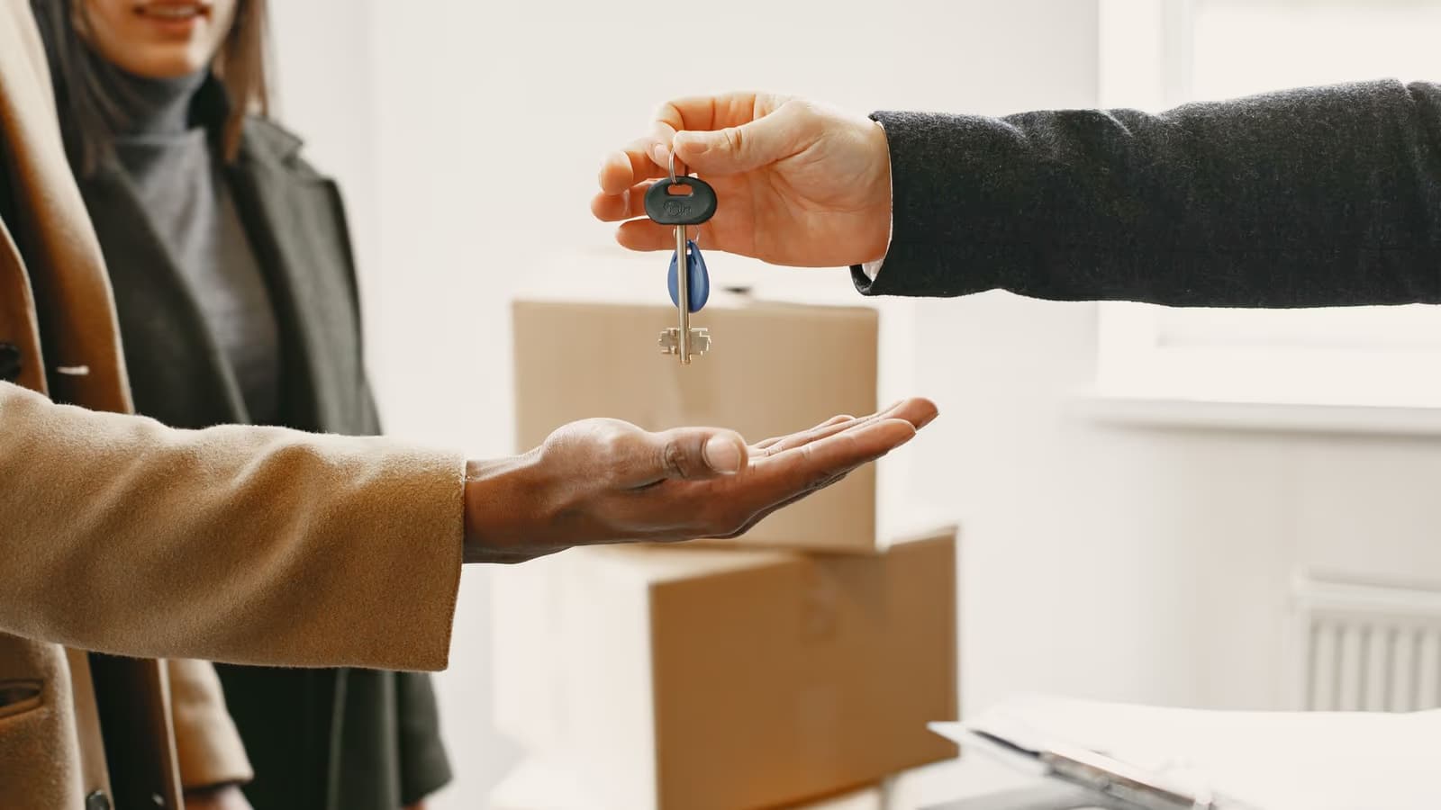 Remise des clés d'une maison, d'une main à une paume ouverte devant des cartons de déménagement, moment de l'accès à la propriété