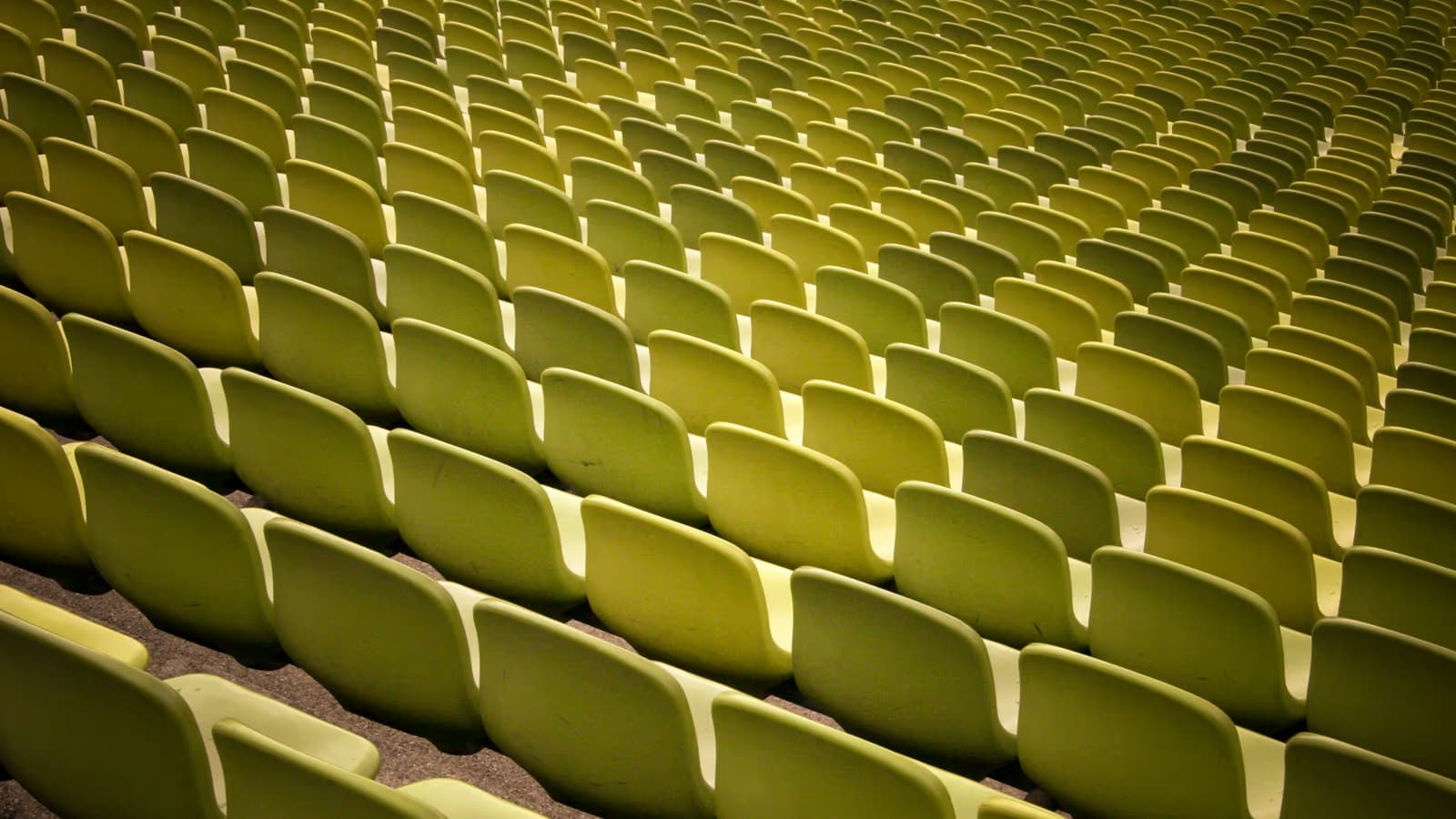 Rangées de sièges vides en plastique vert clair dans les gradins déserts d'un stade, vue graphique en diagonale d'une tribune sans public