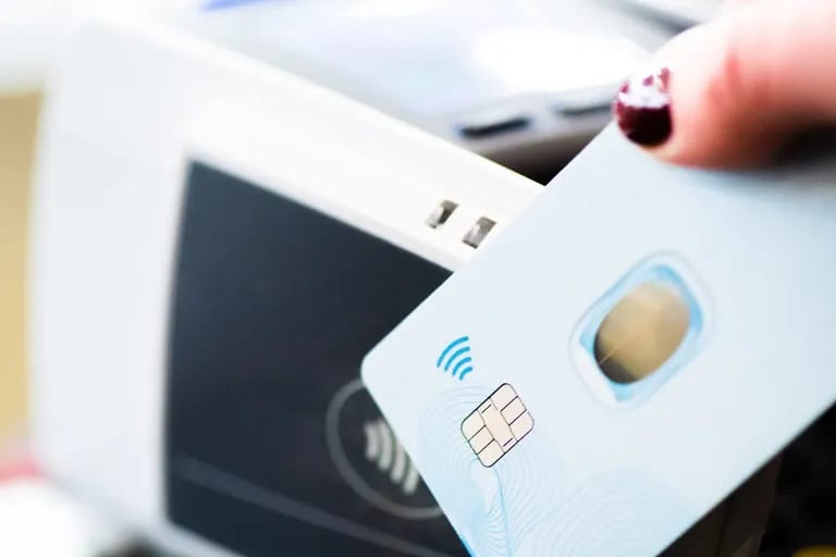 Main présentant une carte bancaire sans contact devant un terminal de paiement