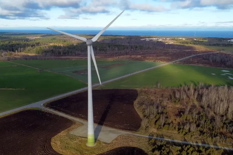 Éolienne blanche surplombant des champs verts près du littoral