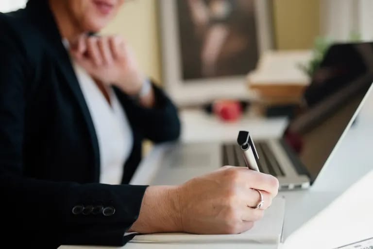 Professionnelle prenant des notes près d'un ordinateur portable et d'une carte bancaire